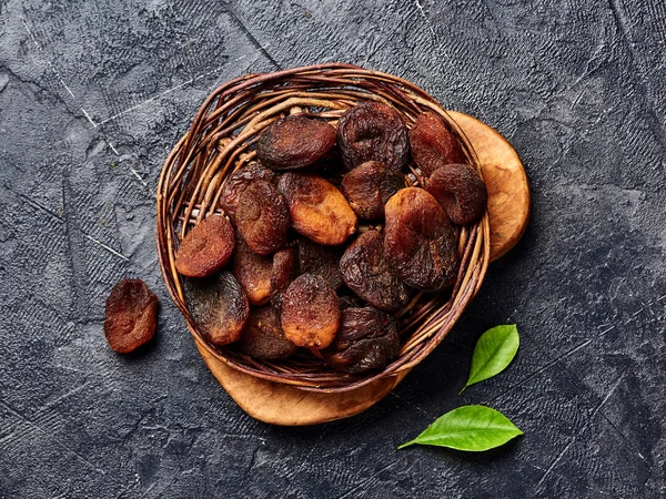 Brown sun dried apricots on black table. Top view.