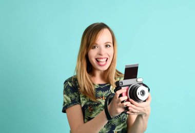 Yeşil arka planda fotoğraf makinesi olan genç ve güzel bir kadın.