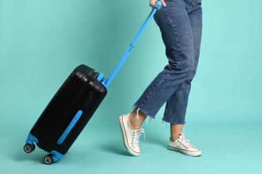 Yeşil arka planda bagajı olan genç bir kadın.