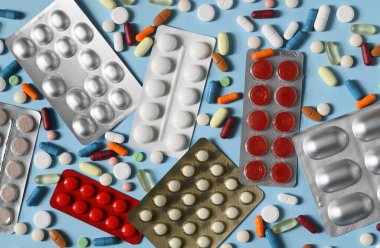 Mavi arka planda birçok hap ve kapsülün düzenlenmesi