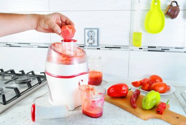 Tanınmayan kişi sebze taze sebze, saydam bir cam içine dökülür kahvaltı için lezzetli meyve suyu yapmak için meyve sıkacağı içinde presler. Her şey masada mı