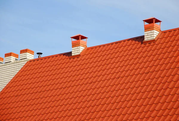 Çatı inşaat. Metal çatı çatı koruma kar kurulu, ev yapımı tetikte kar ile kapatın. Yeni kırmızı kiremitli çatı ile metal baca evin çatı inşaat dış.