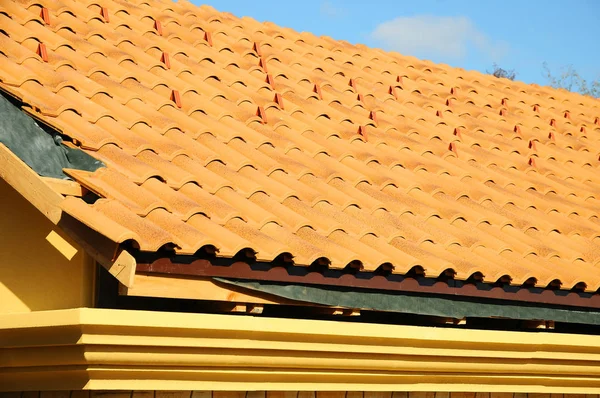 Střecha domu s taškovou střechou na modré obloze. Detail dlažby a rohová montáž na střechu, horizontální. — Stock fotografie