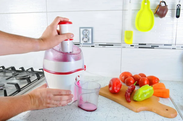 Tanınmayan kişi sebze taze sebze, saydam bir cam içine dökülür kahvaltı için lezzetli meyve suyu yapmak için meyve sıkacağı içinde presler. Her şey masada mı