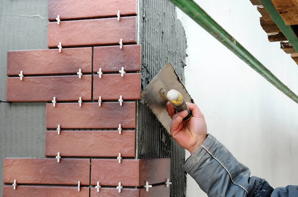 Tegelzetter bouwvakker installeren decoratieve tegels op de gevel van het gebouw. Geïsoleerde en gepleisterde gevel. — Stockfoto