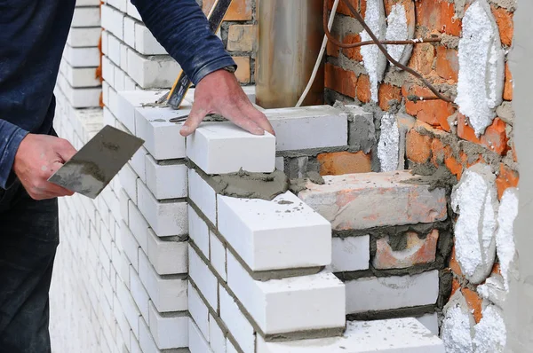 Bir tuğlacı işçi wite blokları ve kalamar tuğla duvar eklemleri dış duvar mala macun bıçak açık yükleme bir closeup.