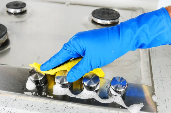 Cleaning a gas stove. Hand protection gloves when cleaning the kitchen. Stock Picture