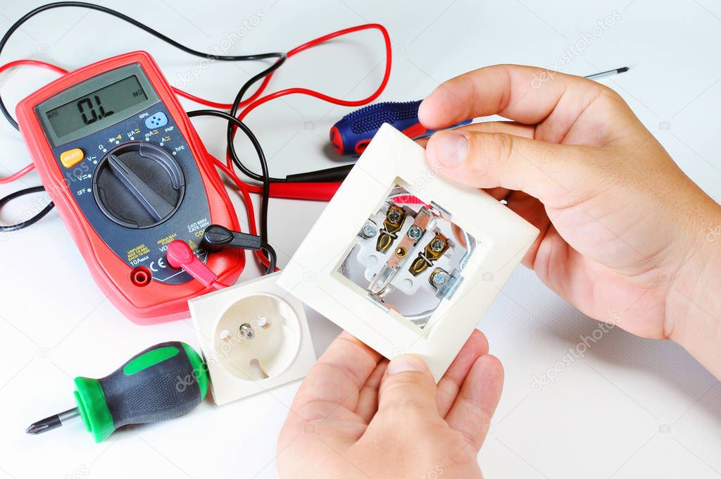 electrician hands with socket. electricity and people concept. digital multimeter. screwdriver