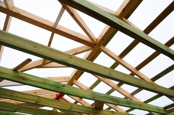 Installation of wooden beams at construction the roof truss system of the house.