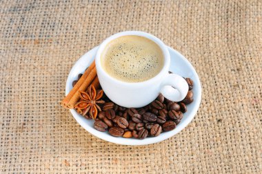 Bir fincan sıcak kahve çuval bezi arka plan üzerine bir daire üzerinde. Bir fincan sıcak kahve