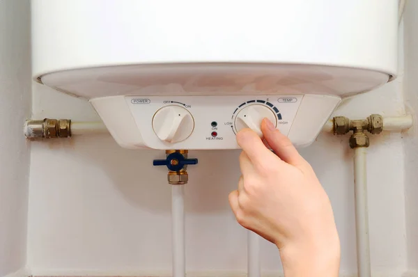 Mãos mulheres jovens definir a temperatura da água na caldeira elétrica. Close up de mãos femininas girando o punho de uma caldeira elétrica . — Fotografia de Stock