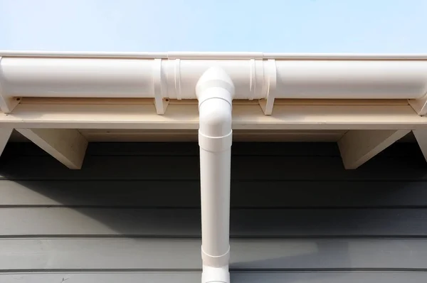 New rain gutter on a home against blue sky. New roof. — Stock Photo, Image