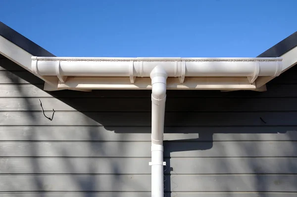 Nieuwe regengoot op een huis tegen blauwe hemel. — Stockfoto