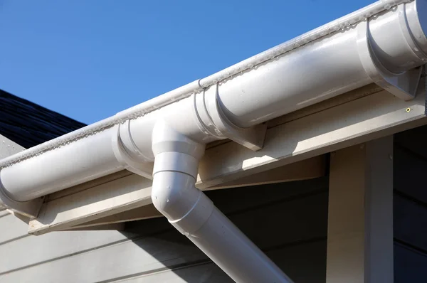 Nieuwe regengoot op een huis tegen blauwe hemel. — Stockfoto