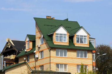 Kiev, Ukrayna - 15 Nisan 2017: Metal çatı. Yağmur oluk boru hattı Downspout boru ve Attic Mansard pencere ile. Çatı inşaat, çatı onarım. Plastik pencere ve yeşil bir çatı ile ev.