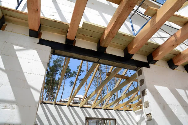 Die Holzkonstruktion des Gebäudes. Holzrahmenbau. Dachkonstruktion aus Holz. Foto für zu Hause. Hausbau. Montage von Holzbalken beim Bau des Dachstuhlsystems des Hauses. — Stockfoto