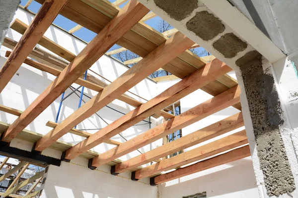 The wooden structure of the building. Wooden frame building. Wooden roof construction. photo for home. house building. Installation of wooden beams at construction the roof truss system. Door concrete lintel with unfinished house construction. — Stock Photo, Image