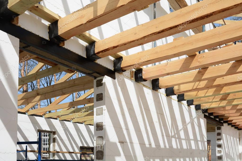The wooden structure of the building. Wooden frame building. Wooden roof construction. photo for home. house building. Installation of wooden beams at construction the roof truss system. Door concrete lintel with unfinished house construction.