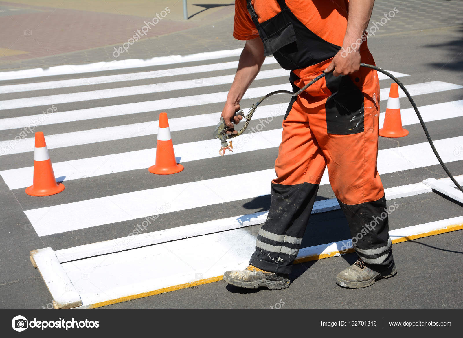Worker is painting a pedestrian crosswalk. Technical road man worker