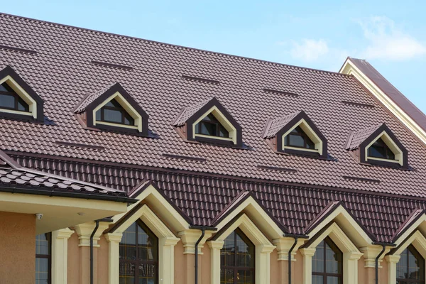 Dormer windows on metal roof. A house with a roof made of metal roofing with mansard windows and rain gutter. Metal Roofing.