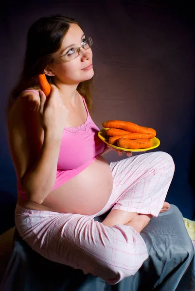 Ciąży i odżywianie - Kobieta w ciąży z dojrzałych marchew. Ładna dziewczyna w ciąży z rozmarzone spojrzenie. — Zdjęcie stockowe
