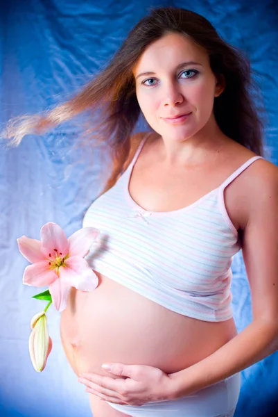 Dziewczyna w ciąży z kwiatem. Kobieta w ciąży z lily. Kobieta w ciąży, trzymając jej brzuch, sam — Zdjęcie stockowe