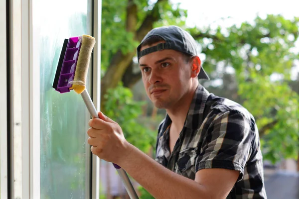 Selectieve aandacht van een jonge man reinigen venster met mop. De wasmachine van het venster. Professioneel schoonmaakbedrijf. — Stockfoto
