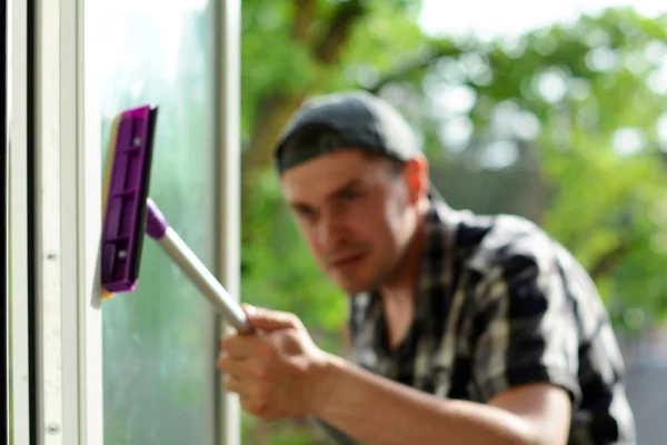 Wazig focus van een jonge man reinigen venster met mop. De wasmachine van het venster. Professioneel schoonmaakbedrijf. — Stockfoto