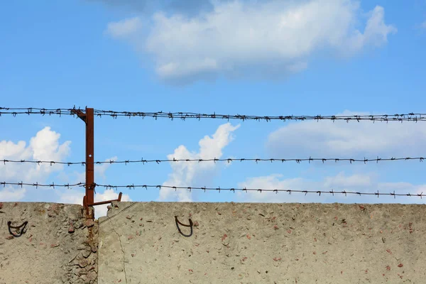 Mavi gökyüzü arka plan üzerinde dikenli tel ile beton çit. — Stok fotoğraf