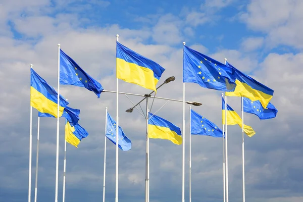 Drapeaux de l'Ukraine et de l'Union européenne (UE) contre le ciel bleu . — Photo