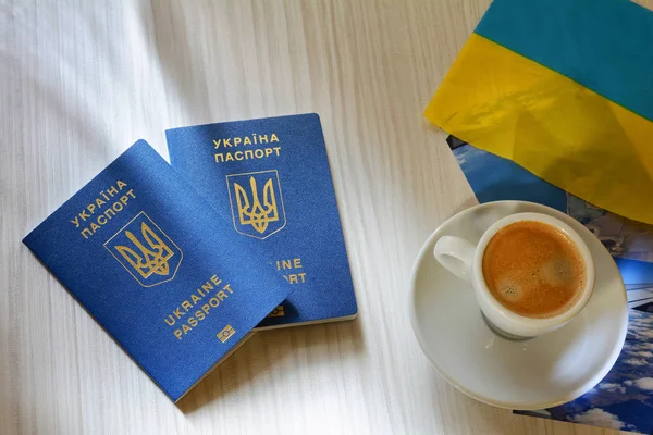 Nouveau passeport biométrique bleu ukrainien avec puce d'identification sur fond en bois. Une tasse de café et un passeport . — Photo