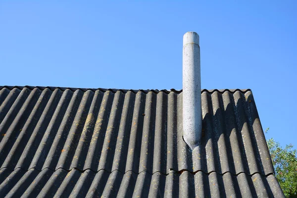 Old roof asbestos roof slates and chimney against blue sky — Stock Photo, Image