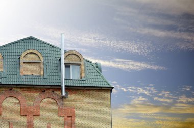 Metal çatı. Evin çatı üstüne yağmur oluk. Modern ev mansard windows mavi gökyüzü ile. Binanın baca.