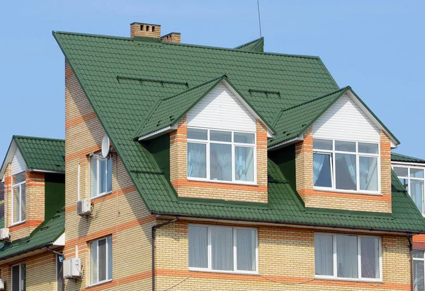 Cubiertas de metal. Rain Gutter and Attic Mansard Window. Construcción de techos. La casa con ventanas de plástico y un techo de metal verde . — Foto de Stock