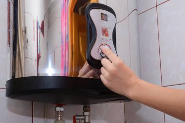 Eller genç kadınlar Elektrikli Kombi su sıcaklığı ayarlayın. Bir elektrikli kazan tanıtıcısı dönüm eller yakın çekim.