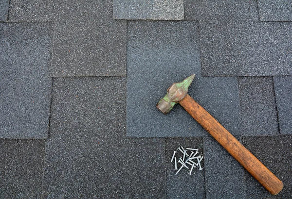 Close up view on Asphalt Roofing Shingles Background. Background. Roof Shingles - Roofing. Asphalt shingles on a roof  with hammer and nails.