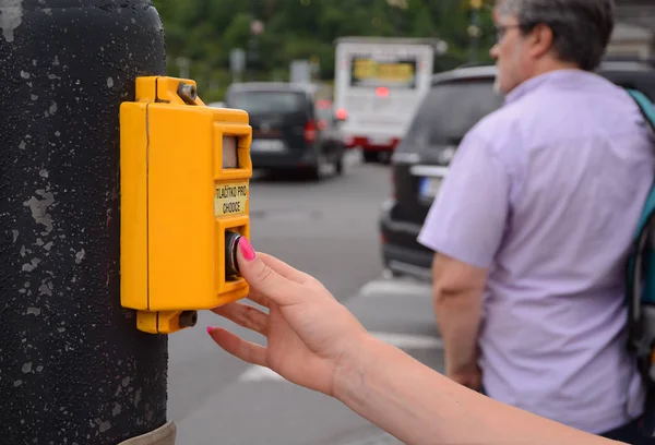 Mano femenina presionando un botón en los semáforos en el cruce peatonal . — Foto de Stock