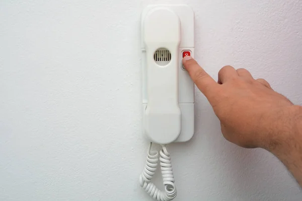 La mano dell'uomo preme il pulsante del citofono la casa. Rispondi all'interfono quando chiamano. Il concetto di sicurezza domestica . — Foto Stock