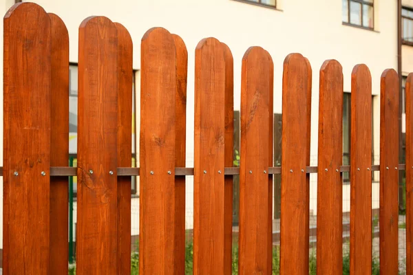 Land stijl houten hek met een huis achter. Close-up op houten hek. — Stockfoto