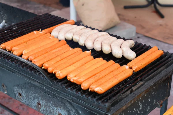 Saucisses fraîches et hot-dogs grillés en plein air sur un barbecue à gaz. Gros plan de saucisse sur le gril — Photo