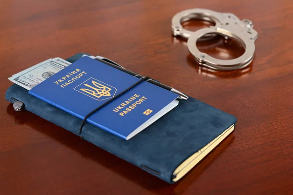 Pasaporte biométrico ucraniano y esposas en la mesa.Pasaporte biométrico ucraniano. En Ucrania, la corrupción debe ser castigada por la ley y no ser un hogar para personas corruptas. . — Foto de Stock