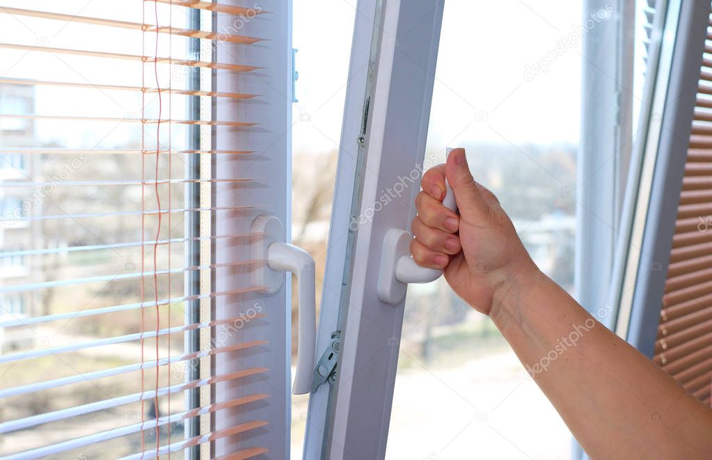 Adult woman's hand opening a window for ventilation