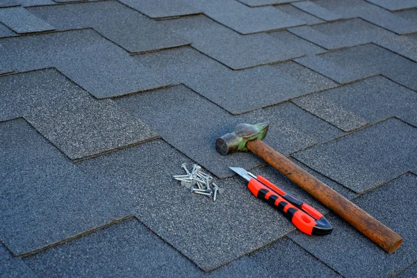 Close up view on asphalt shingles on a roof  with hammer,nails and stationery knife background.