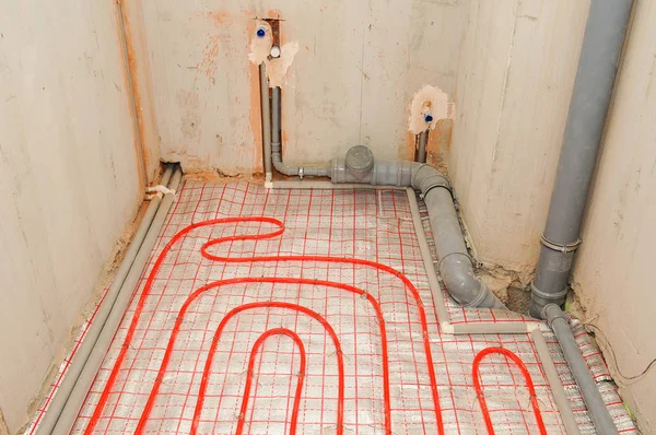 在房屋建造中的银反射性材料上安装地下热水管 — 图库照片