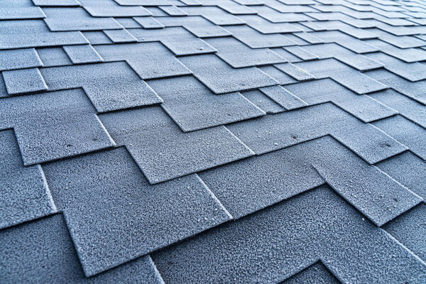 View on asphalt roofing shingles covered with frost.