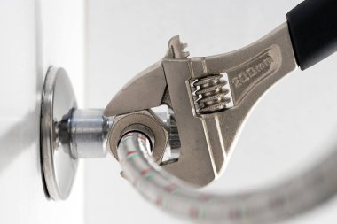 Domestic plumbing connections hoses. Using an adjustable wrench.
