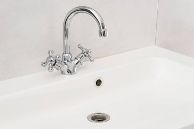 Banyo içi beyaz lavabo ve krom muslukla dolu..