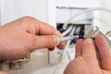 Worker inserts connector of a TV antenna coaxial cable. clipart
