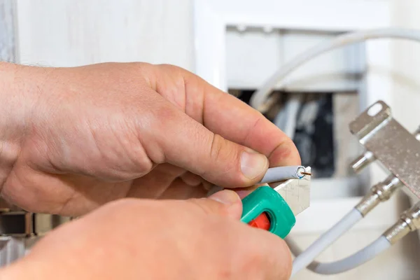 Worker removes insulation before inserting connector of a TV antenna coaxial cable to a splitter.