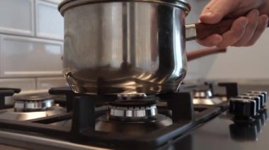 Bir adam modern paslanmaz çelik gaz sobasının ocağını ateşe verir ve tavayı pişirmek için hazırlar..